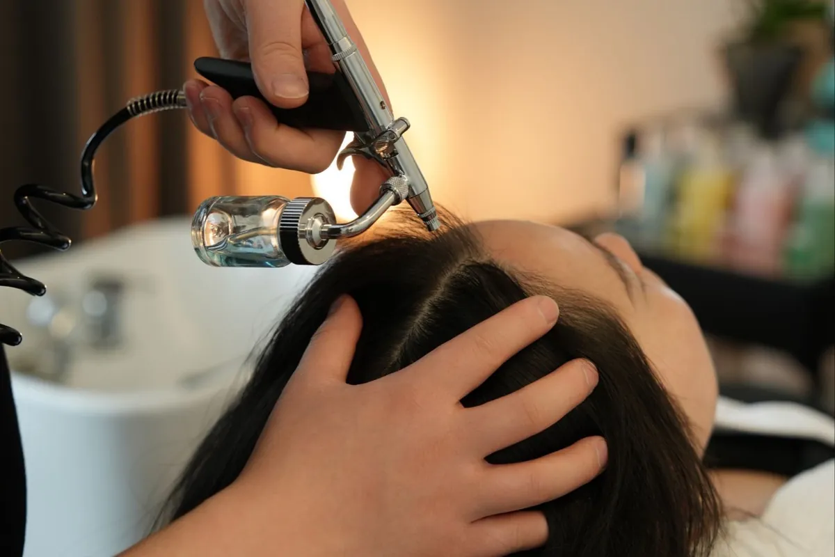 A therapist applying herbal treatment along a client's scalp at Young Hair in San Gabriel.